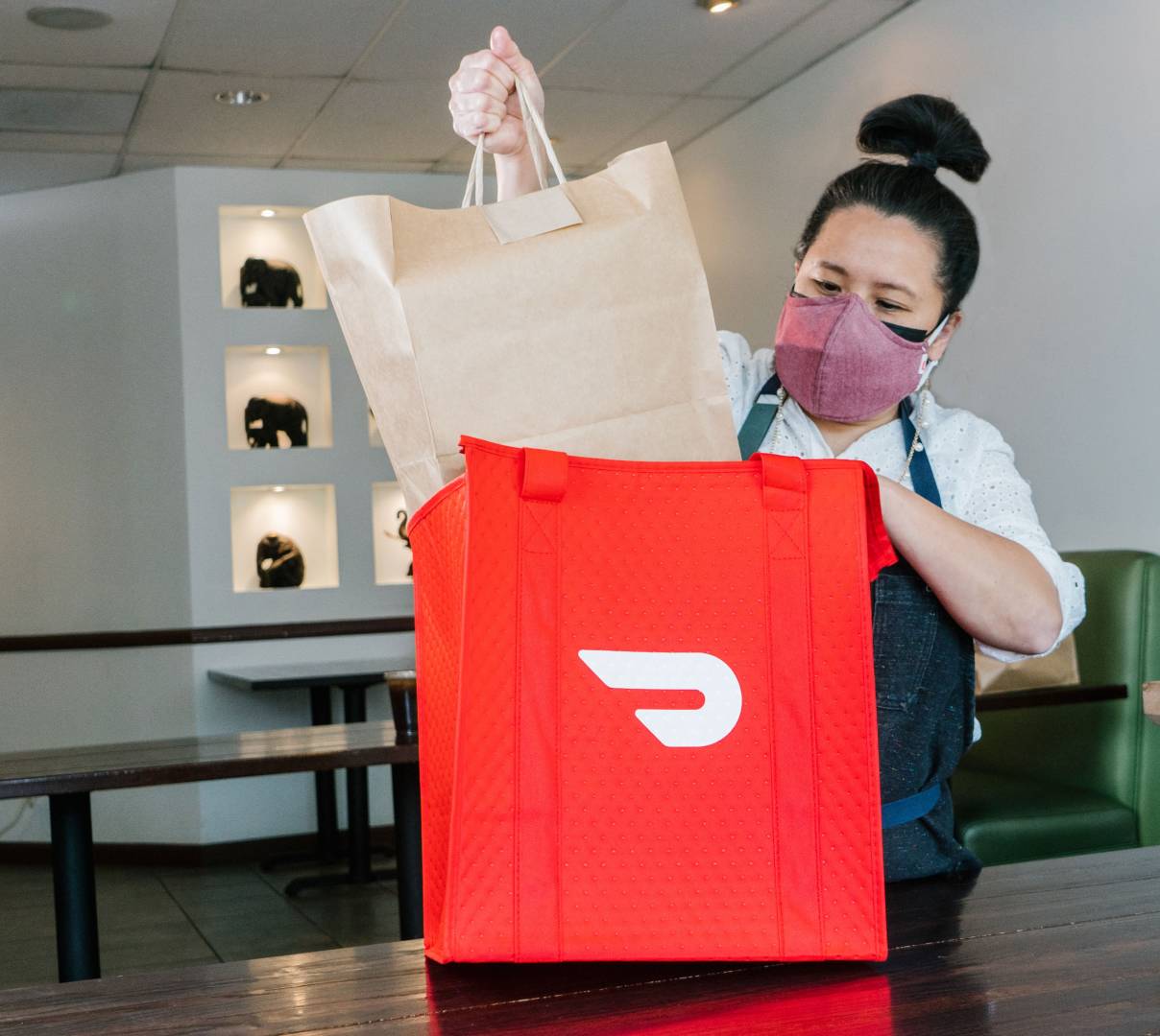 Person putting food in DoorDash bag 