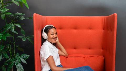 Women wearing headphones and sitting on an armchair