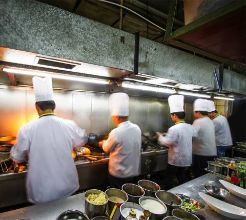 Mx Blog (US/CA/AU/NZ) - Restaurant Location Strategy: How to Choose Where to Open Your Business - Chefs in line cooking (from rear)