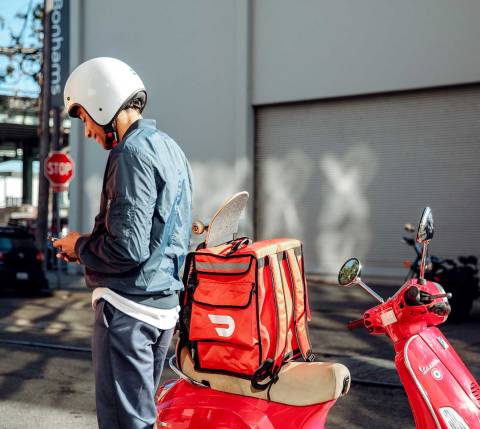 Dasher checking app on the back of a moped