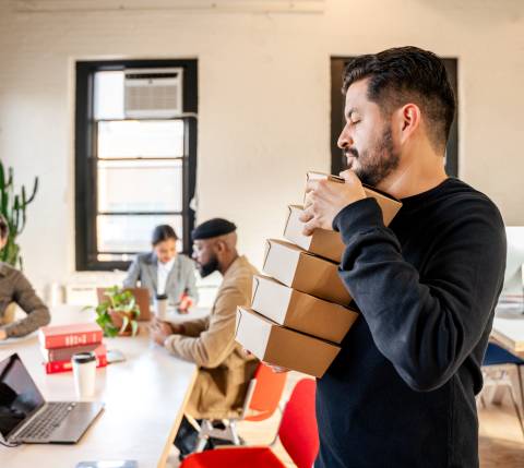 Man carrying takeout boxes in office