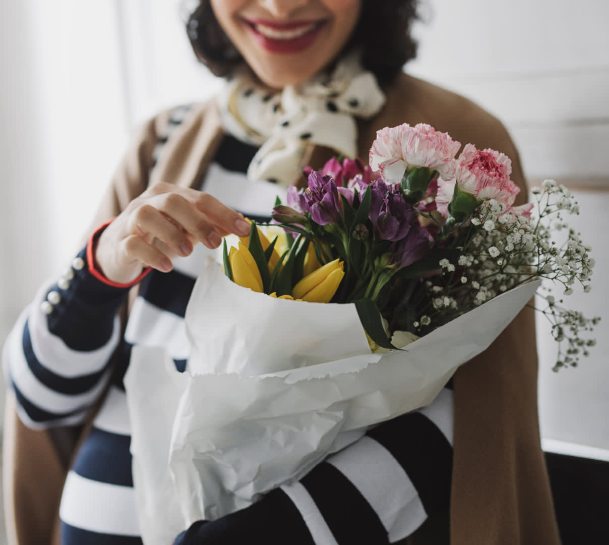 Woman in striped shirt holding bouquet of flowers