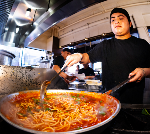 Restaurant worker cooking noodles in a wok