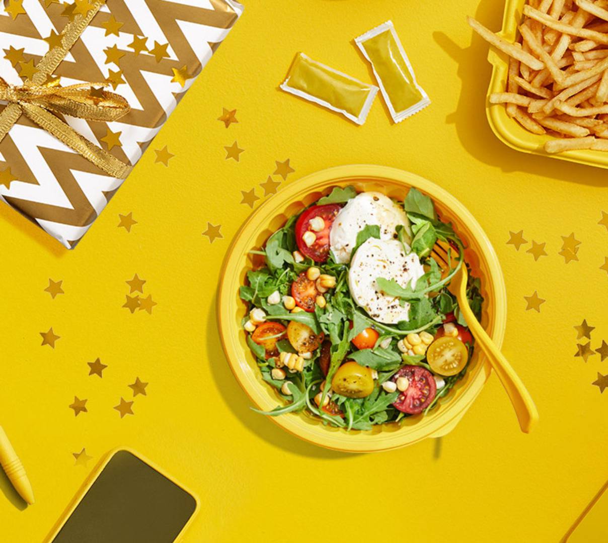 Salad bowl flanked by present, french fries and laptop