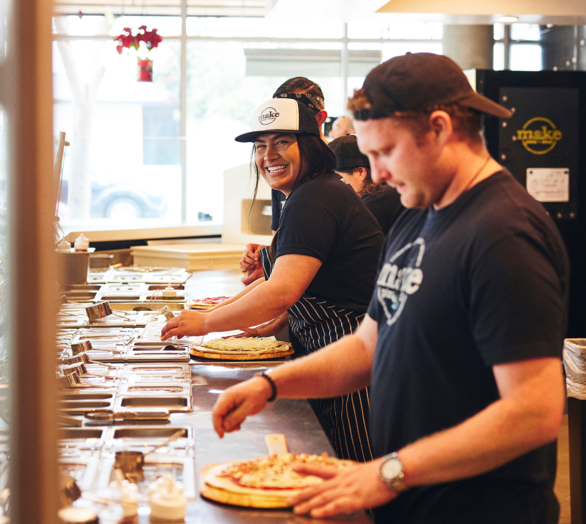 Restaurant service, staff smiling and making pizzas at a restaurant