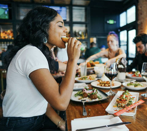 Mx Blog  - 18 Effective Restaurant Promotion Ideas to Grow Your Business - woman biting into food at restaurant