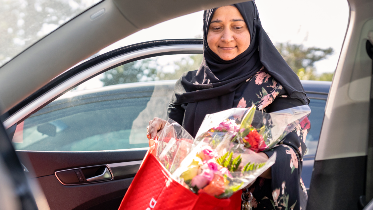 Woman exiting car with DoorDash bag of flowers