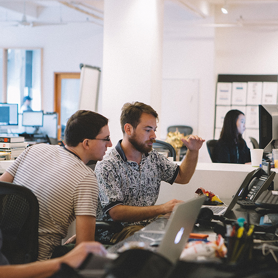 MCD employees discussing an issue at their desks in the office.