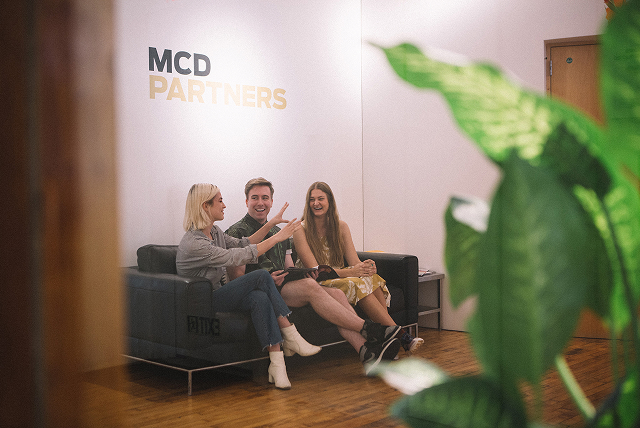 MCD employees talking on a couch in the office lobby.