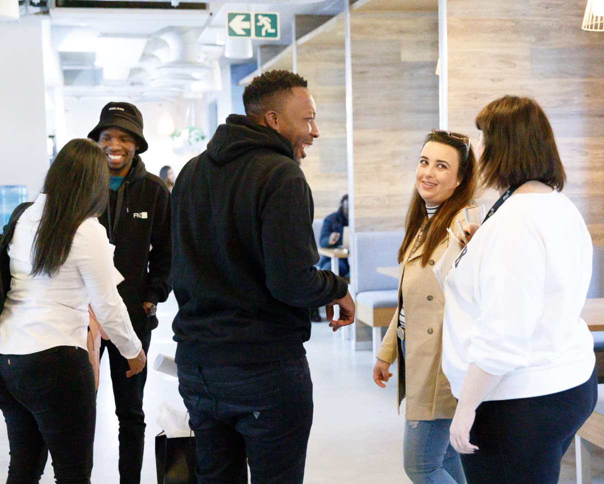 mixed group laughs together will standing in a dining hall