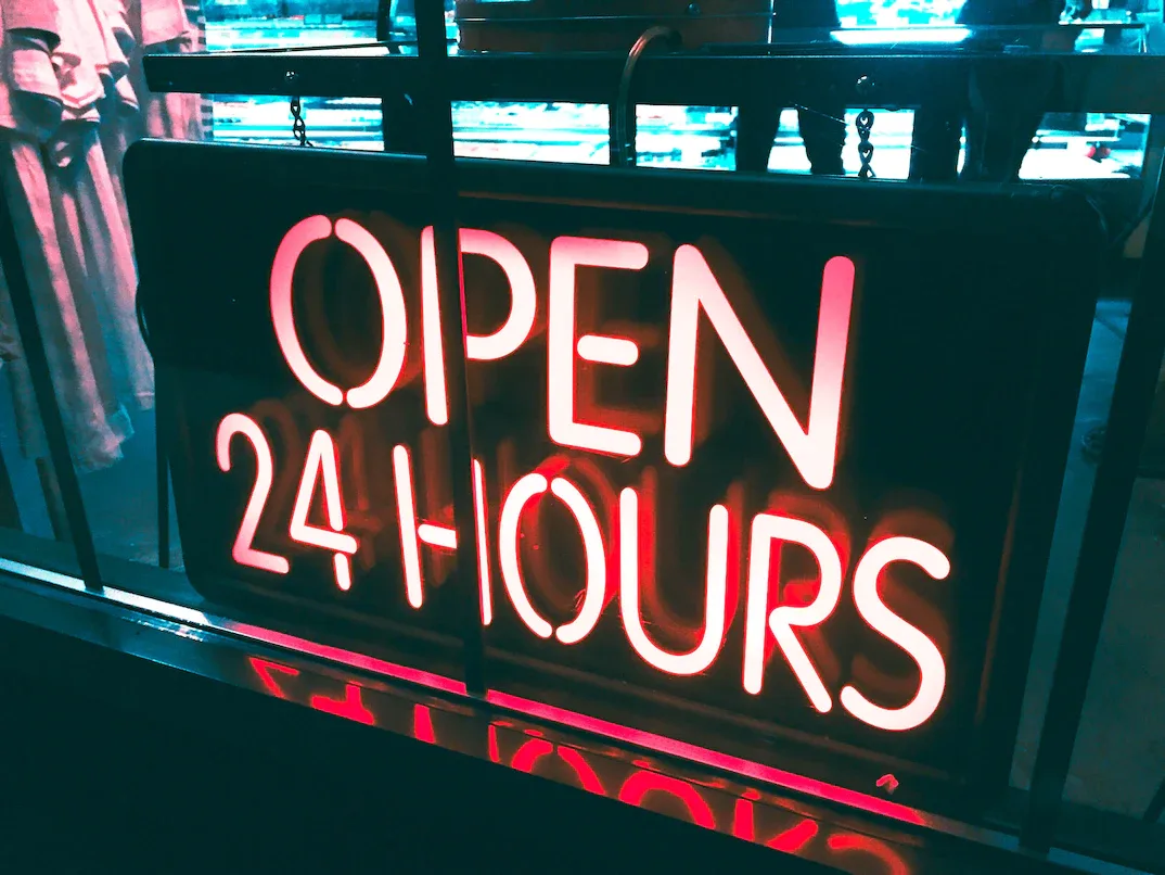 glowing neon "open 24 hours" sign in a storefront