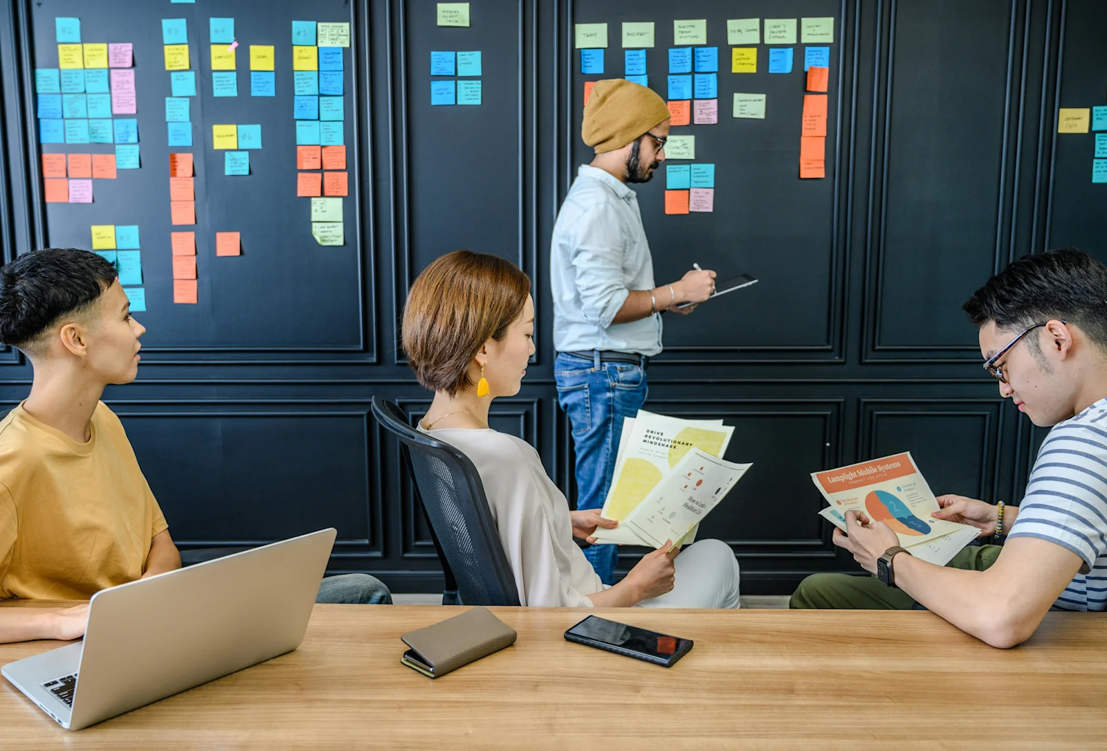 a male employee wearing a beanihaving a discussion with his teammates
