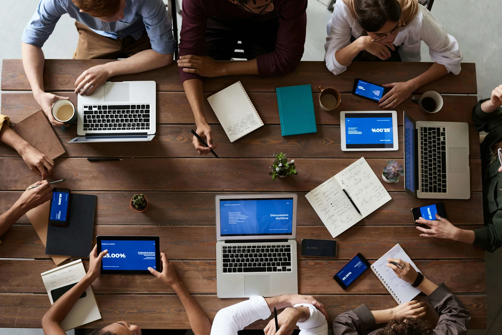 group collaborating around a table with laptops and tablets