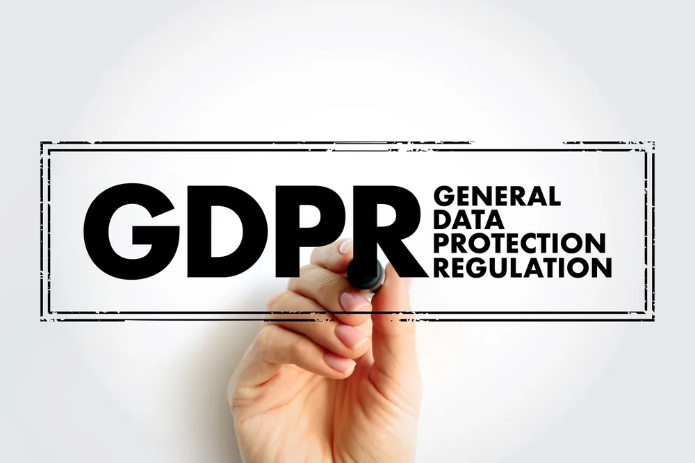 a hand writing the word 'GDPR' and its full name, General Data Protection Regulation, on a board