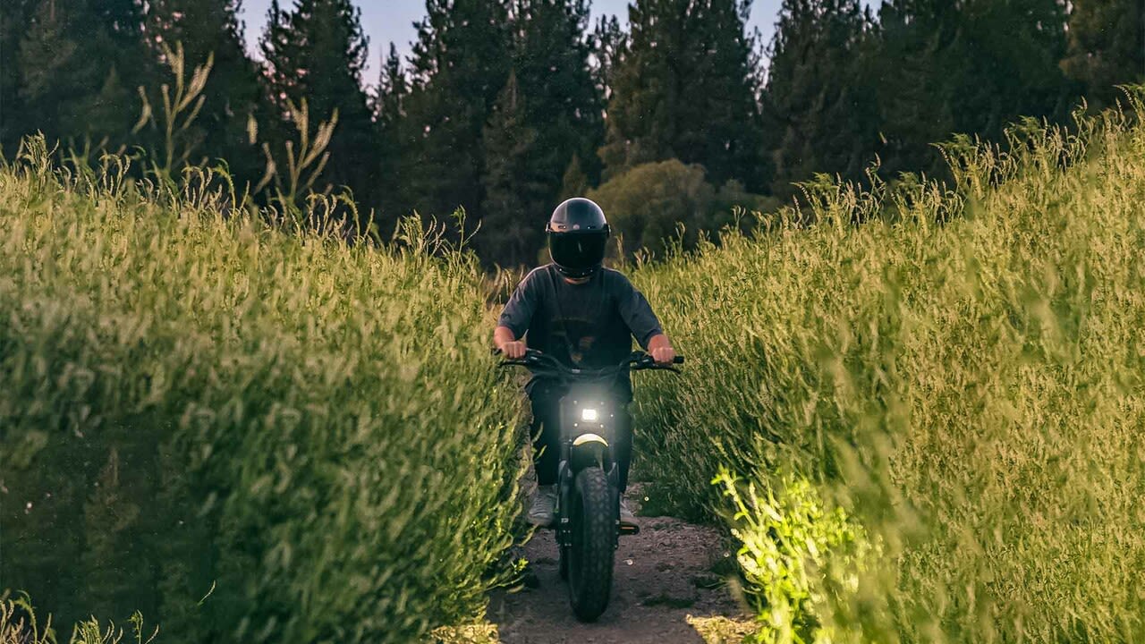 Front view of rider on trail surrounded by tall green grass