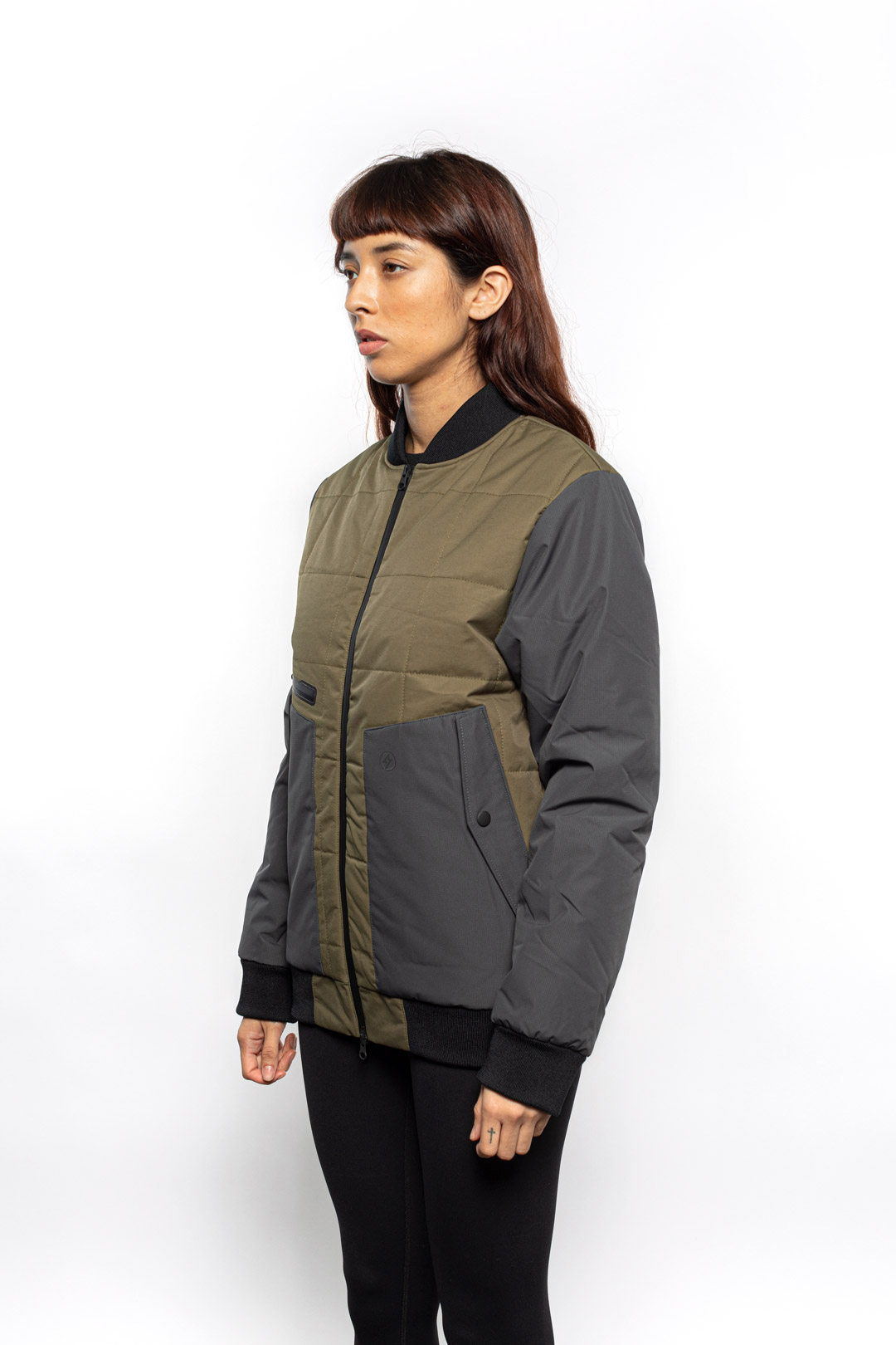 Side view of Female model wearing Sipes Varsity Jacket in dark fatigue colorway.