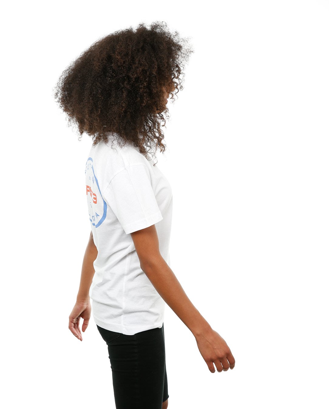 Side view of female model in White Oval Tee on white background.