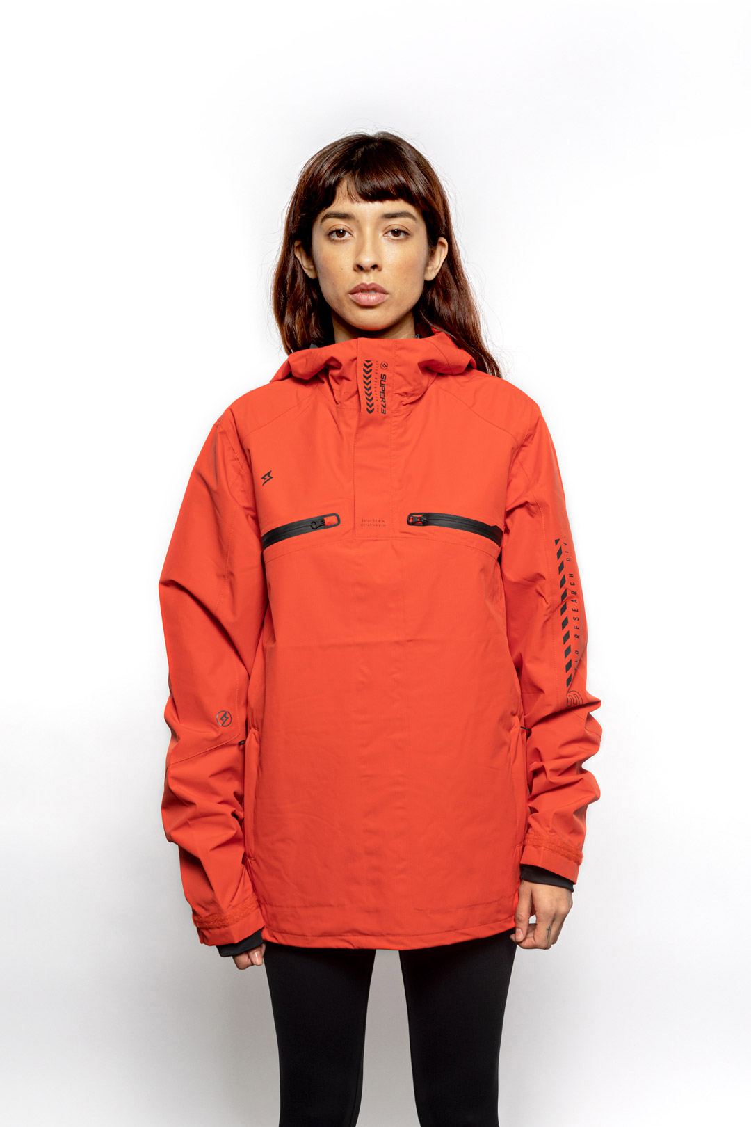 Female model wearing Vale Packable Anorak in blood orange colorway.