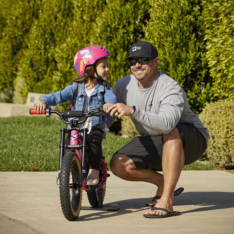 Super73 YouthSeries Lifestyle-01 1080x1080 Father helping daughter learn to ride a bike on the pink Youth Series vehicle.
