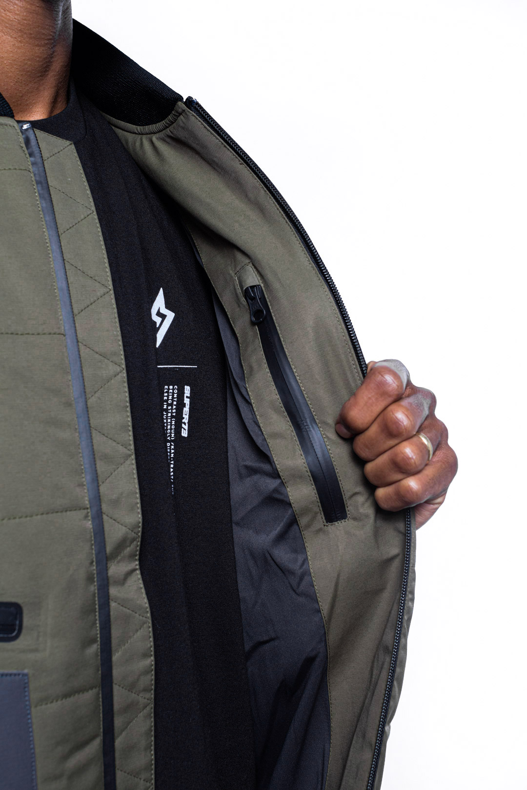 Male model showing inner details of Sipes Varsity Jacket in dark fatigue colorway.