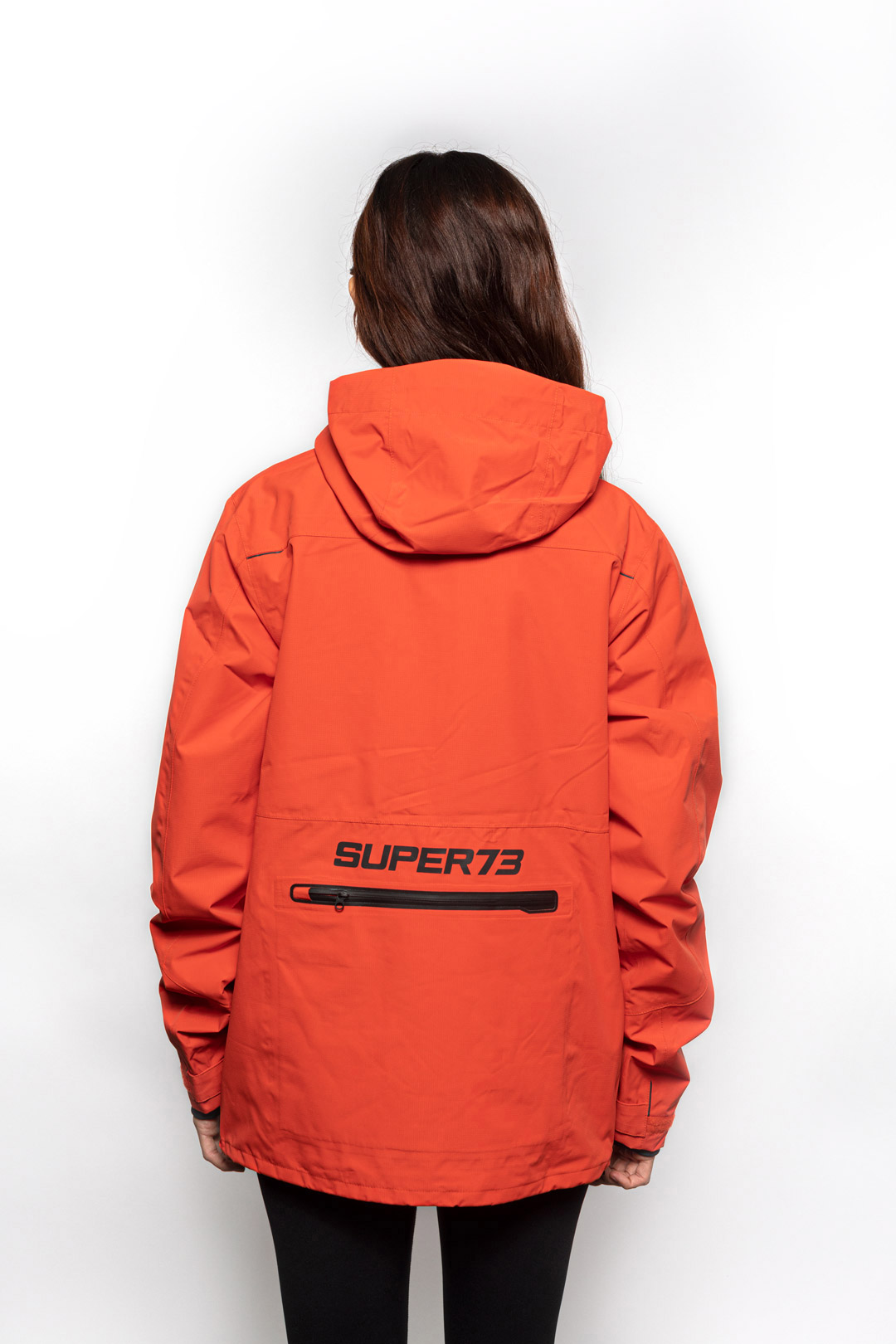 Back view of Female model wearing Vale Packable Anorak in blood orange colorway.
