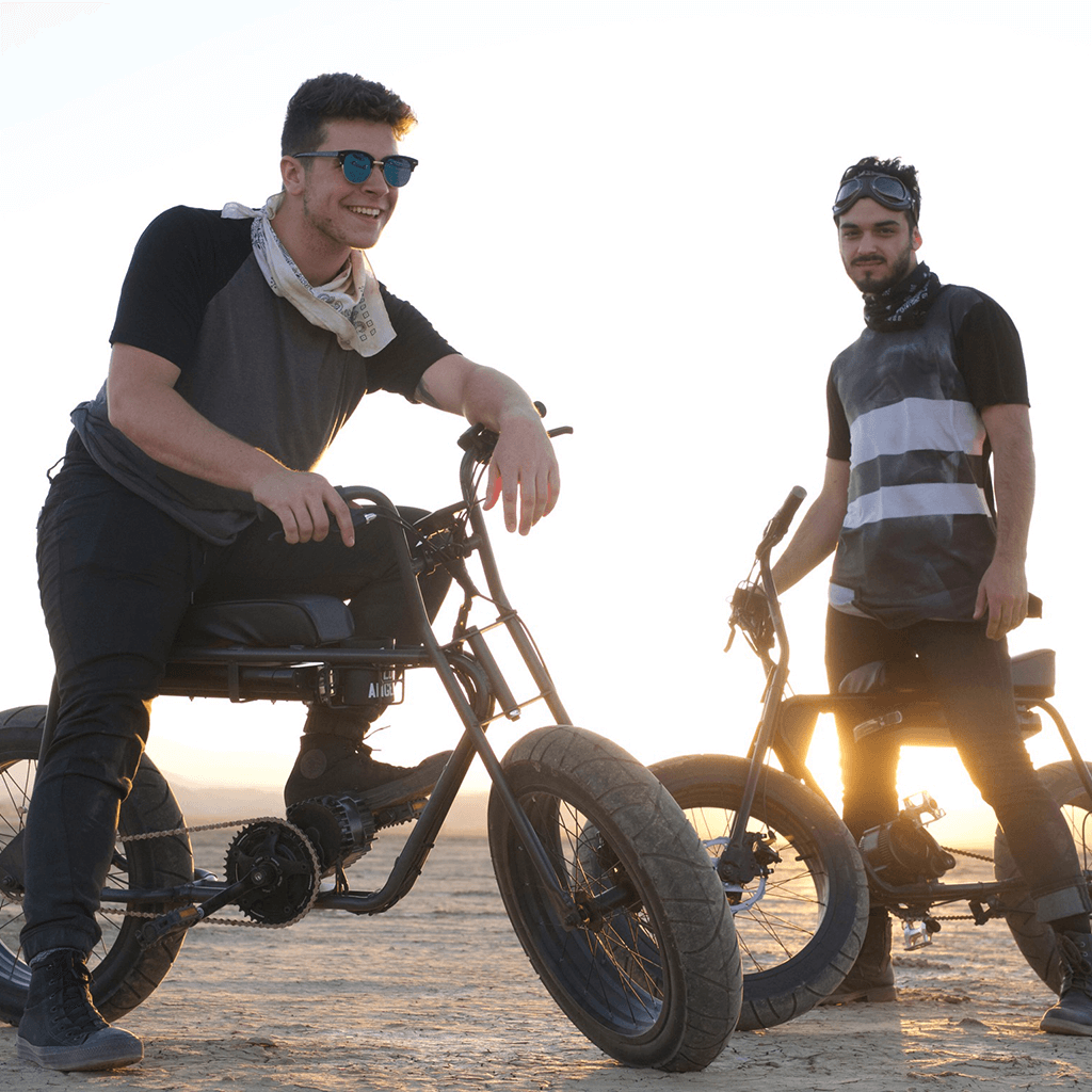 Super73 About 2016  Two men hanging out on black Super73's in the desert with the sun setting in the background.