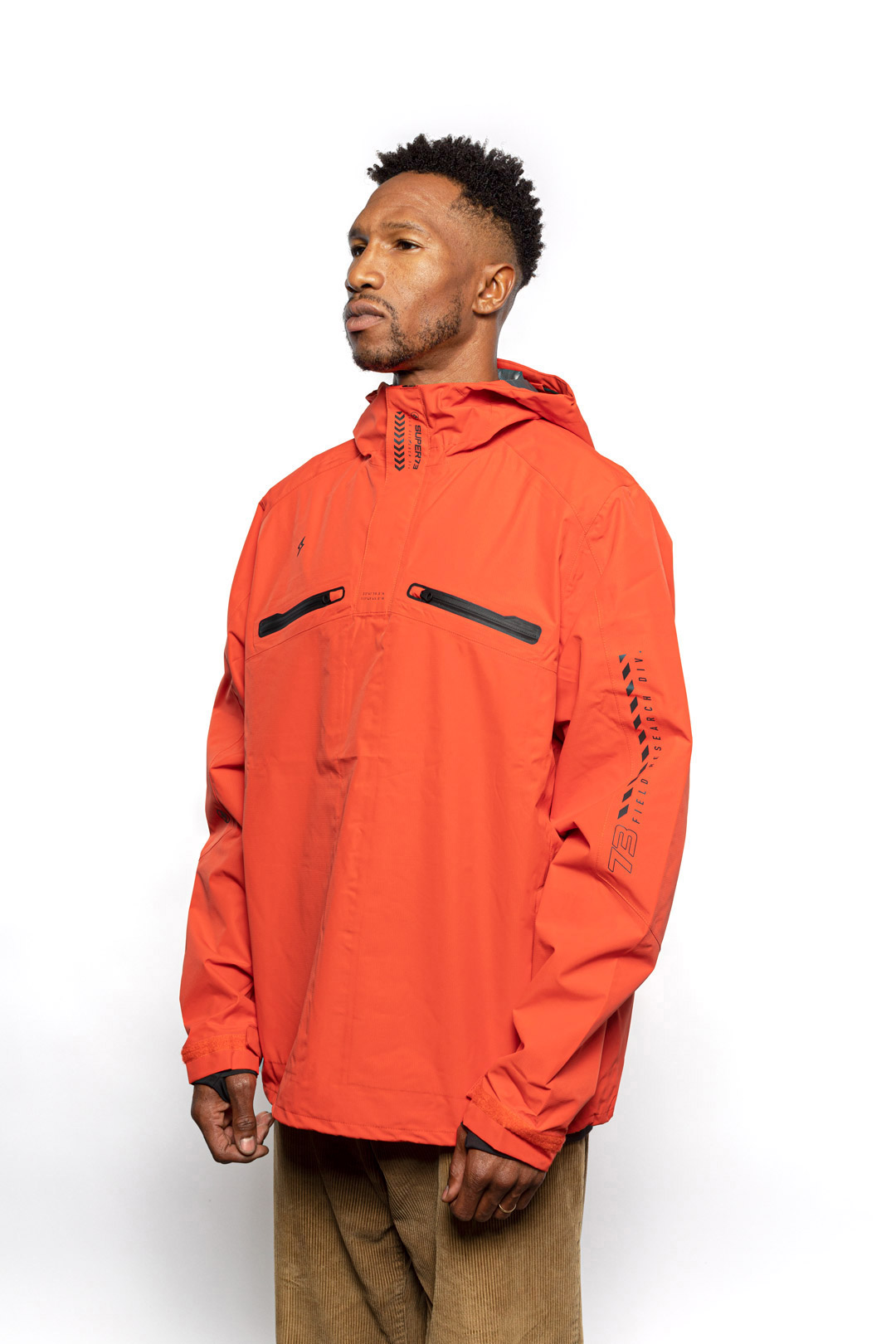 Side view of Male model wearing Vale Packable Anorak in blood orange colorway.