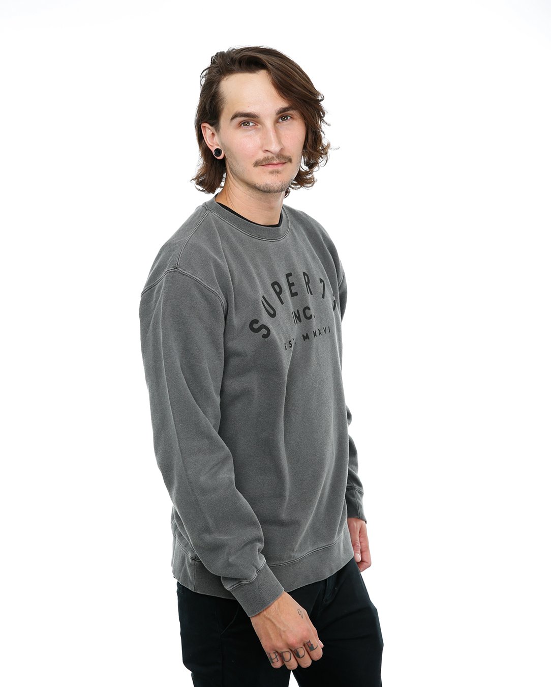 Side view of male model in Pigment Black Classic Crew Sweatshirt on white background.