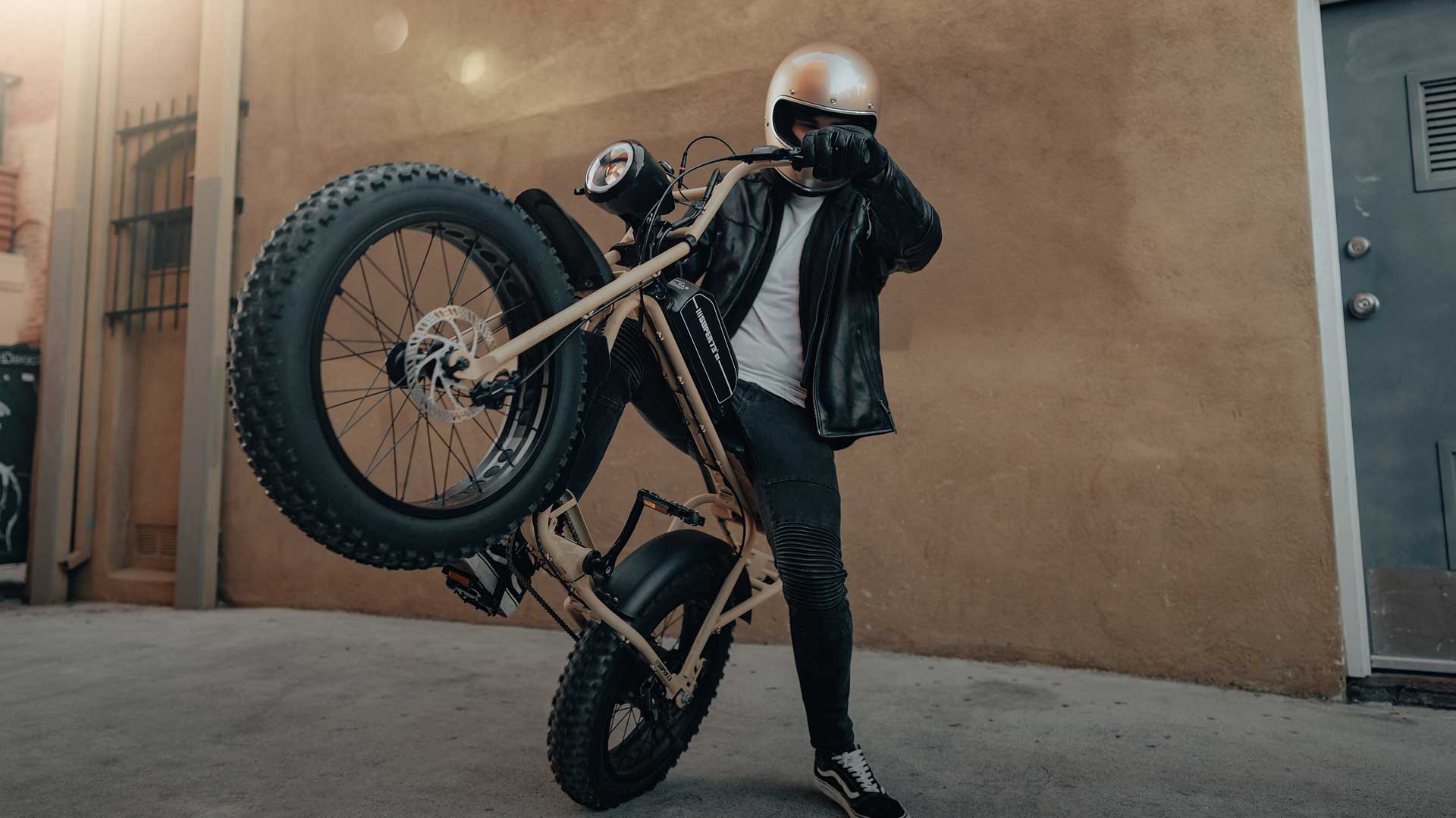 Rider popping wheely on a tan S1 model bike