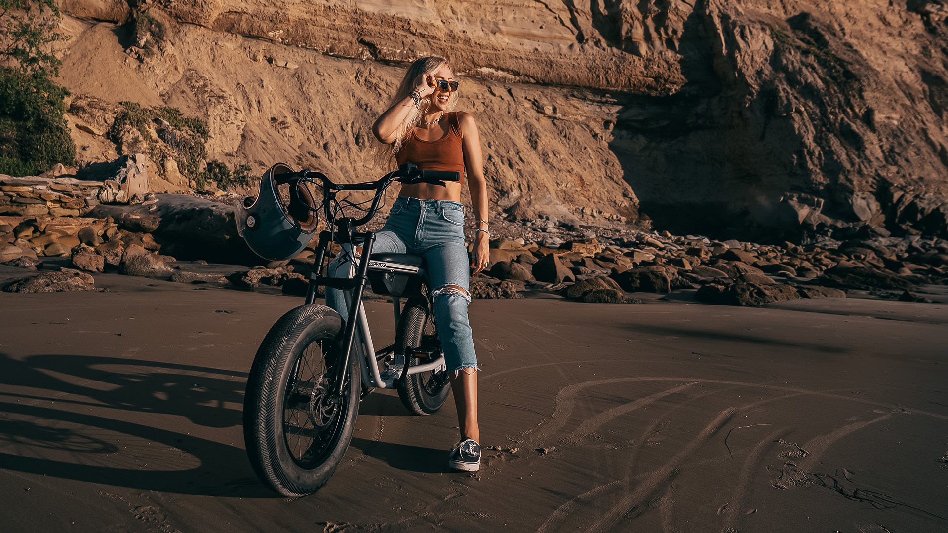 Young blonde woman sitting on her Super73 on a gravel highway looking into the sunset.