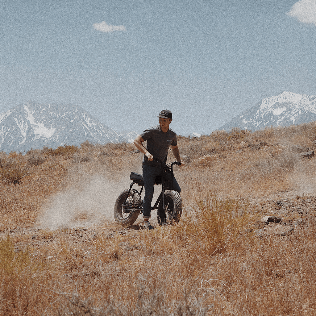 Super73 About 2017 Man riding a Super73 on a dirt road in the High Sierras with mountains in the background.