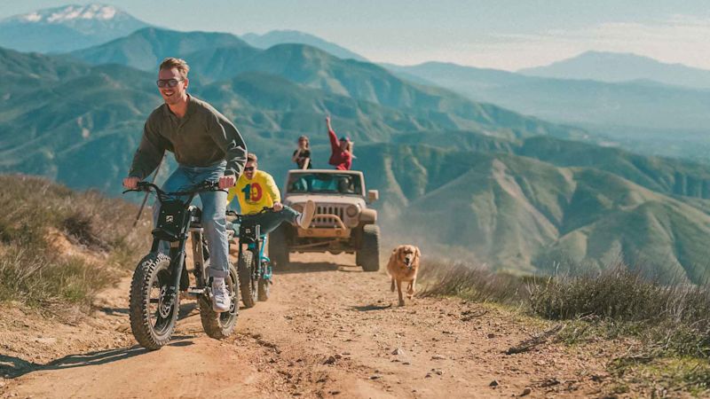 Super73 RX Accessories 1920x1080 Riders outside on dirt trail being followed by dog and jeep wrangler.
