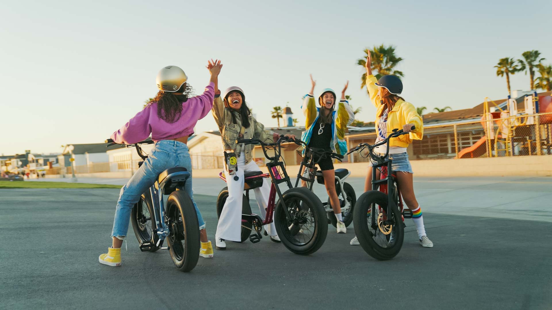 A group of friends high-fiving while riding Super73 ebikes.