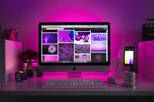 Desktop with pink lighting showing web design images on screen
