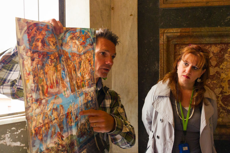A guide helps visitors interpret the frescoes on the Sistine Chapel 