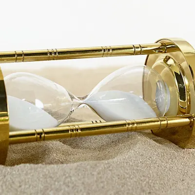 goldene-sanduhr-im-sand-liegend