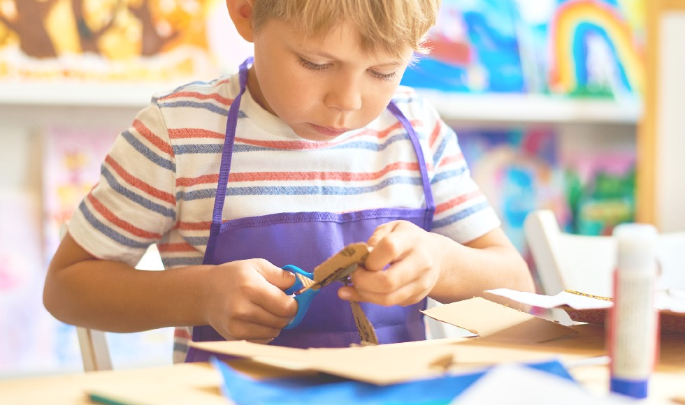 Young boy cutting paper for arts and crafts