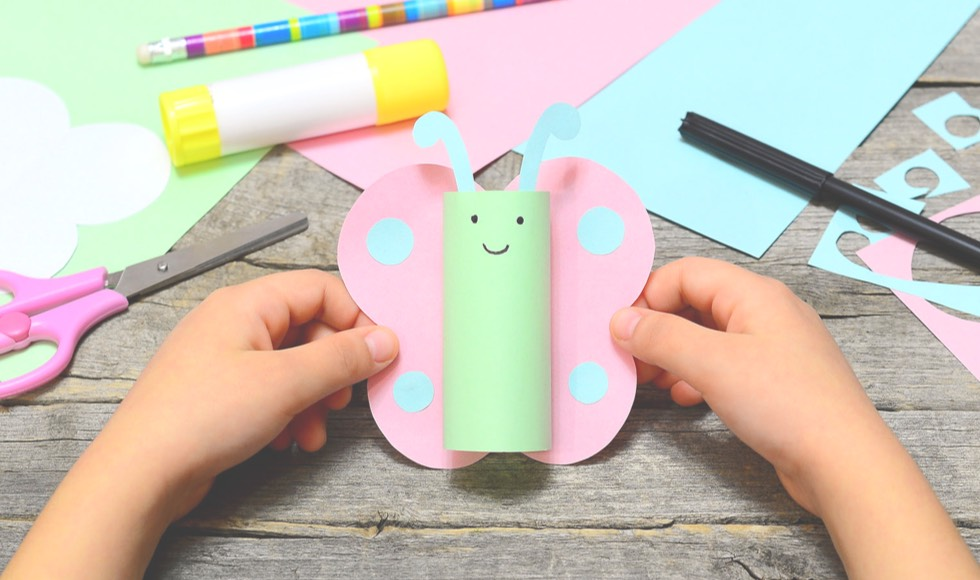 Young girl holding a butterfly paper towel craft