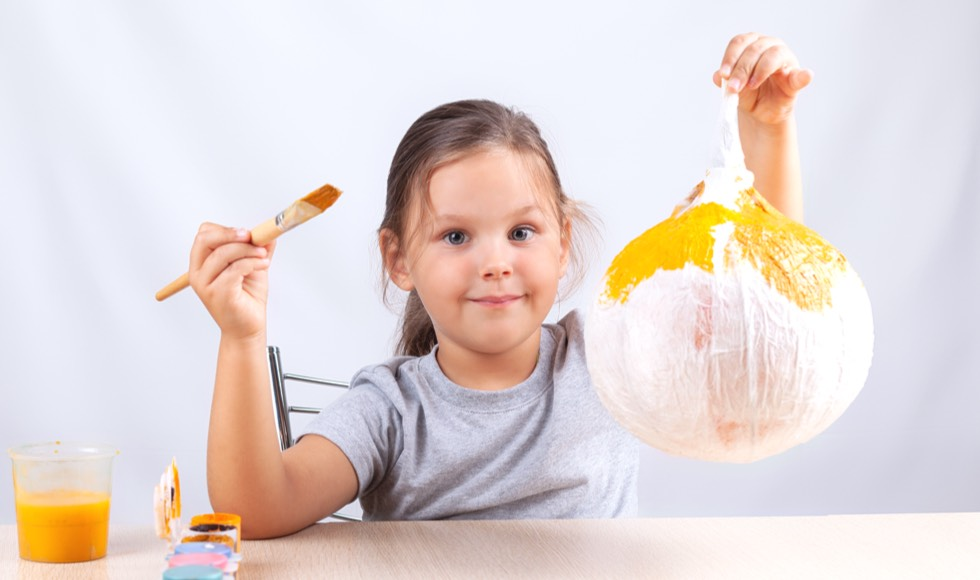 Young girl painting a papier-mâché ball