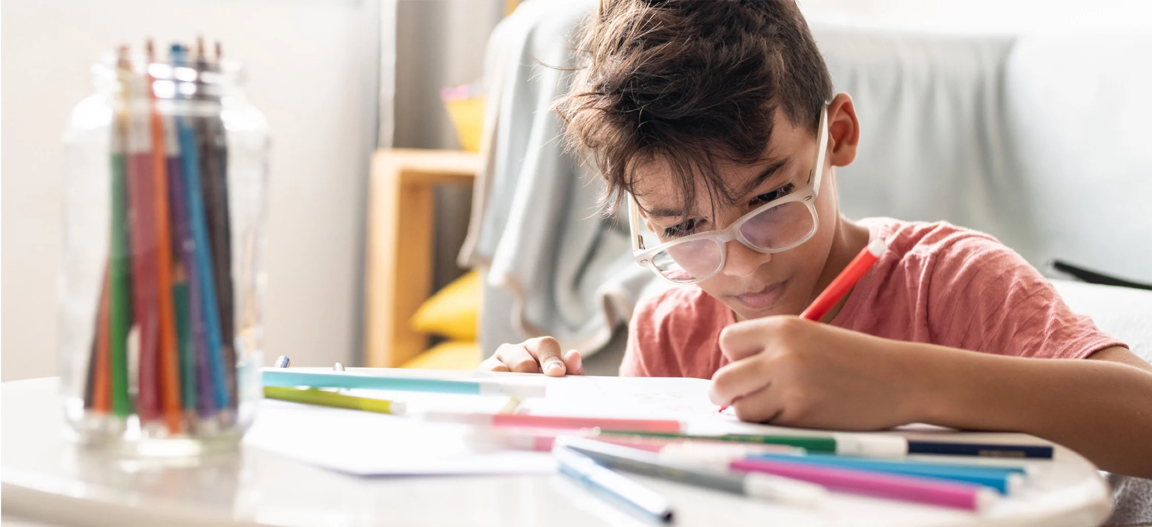 Young boy drawing and doing paper roll craft
