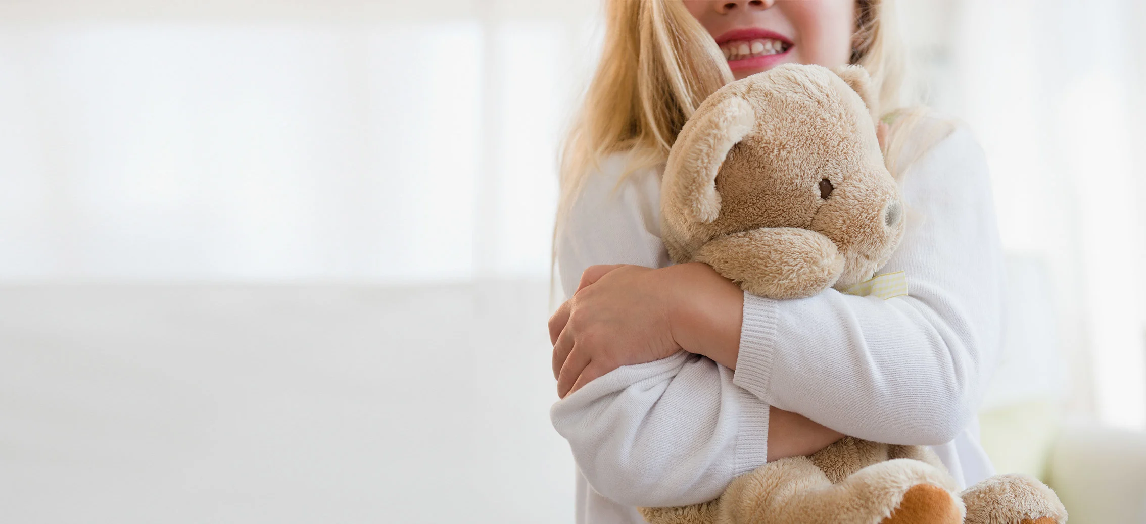 Young girl squeezing teddy bear