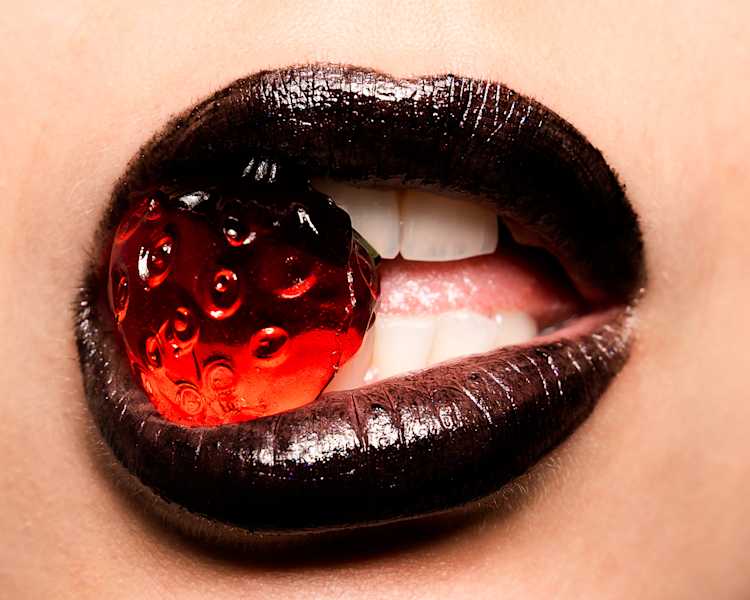 Dark lipstick lips holding a spherical translucent ball.