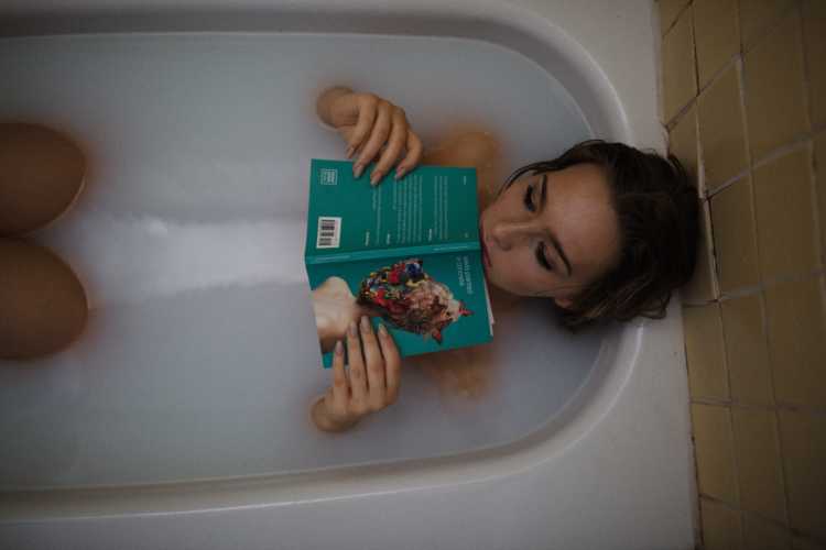 woman in tub with book, thinking about STI treatment