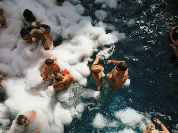 People partying, chatting and drinking on spring break, in a pool with foam.