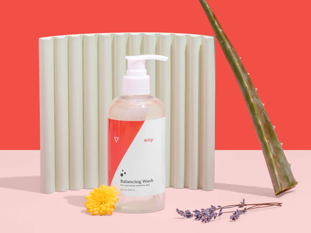 a bottle of balancing wash with an aloe leaf, lavender sprig, and yellow flower