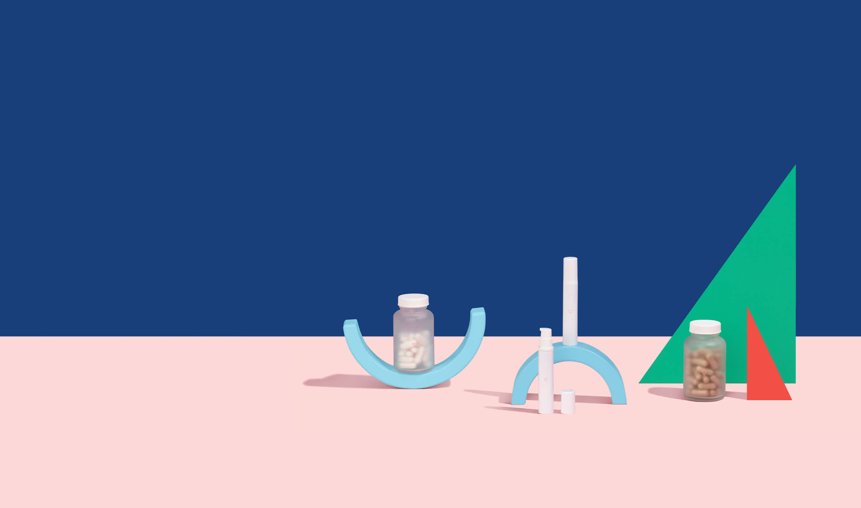 Genital herpes medications balanced on colorful geometric shapes on a pink surface in front of a blue background.