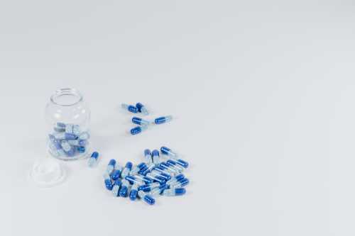 Blue capsules and a glass bottle to represent antibiotics that could cause a yeast infection