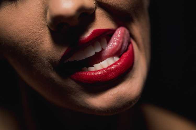 Lips with red lipstick with tongue sticking out.