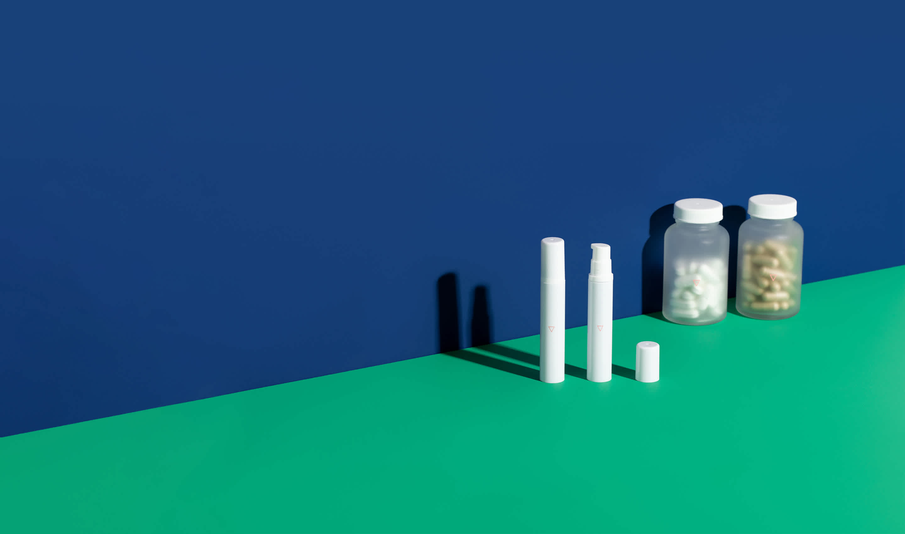 Cold sore medications on a green surface in front of a blue wall