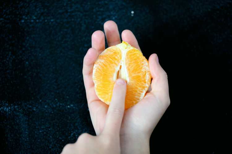 Person holding a half of an orange.